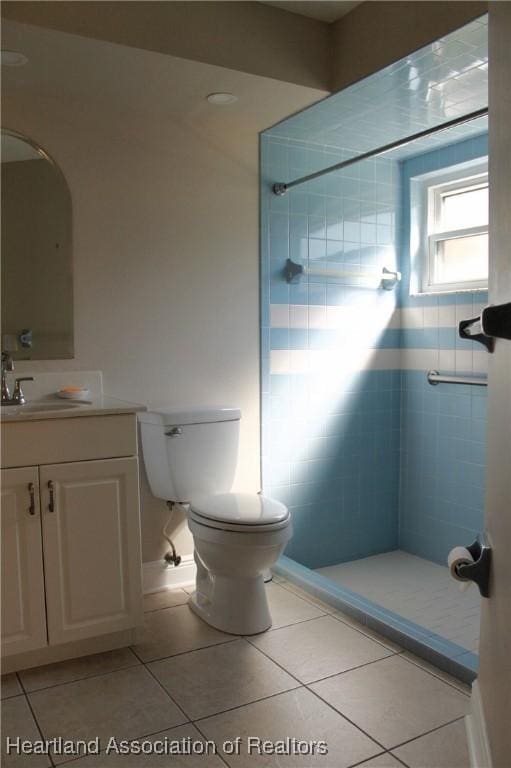 bathroom with tile patterned flooring, a tile shower, vanity, and toilet