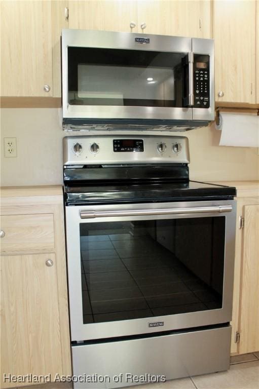 kitchen with light brown cabinetry, stainless steel appliances, and light tile patterned floors