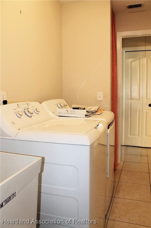 clothes washing area with washer and dryer and light tile patterned floors