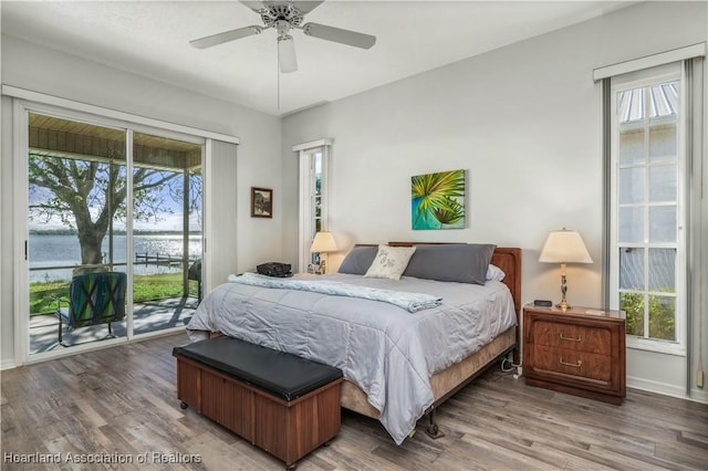 bedroom with access to outside, multiple windows, ceiling fan, and a water view