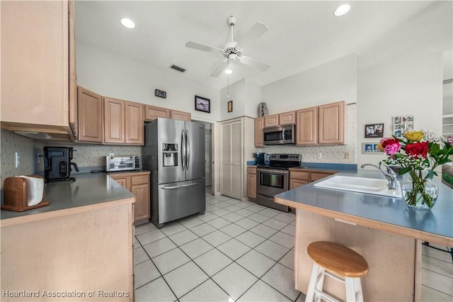 kitchen featuring backsplash, sink, stainless steel appliances, and a breakfast bar area