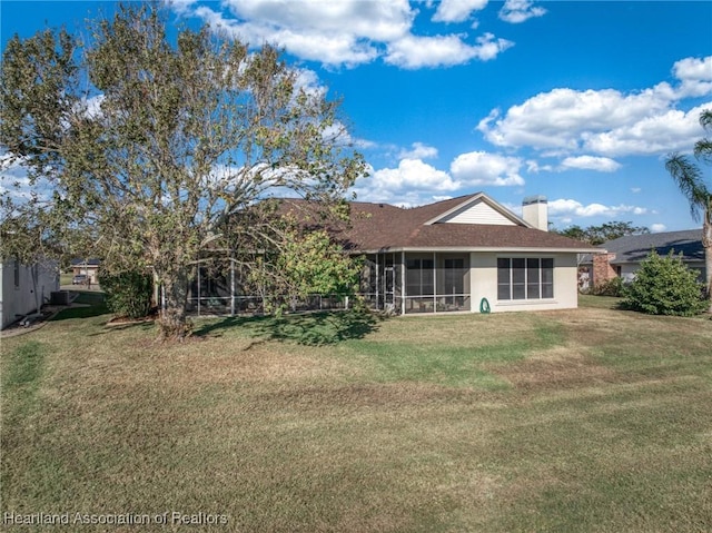 rear view of house featuring a yard and a sunroom