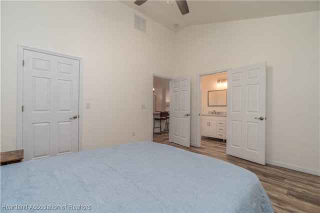 bedroom featuring wood-type flooring, connected bathroom, high vaulted ceiling, and ceiling fan