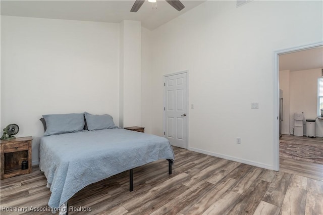 bedroom with hardwood / wood-style flooring, high vaulted ceiling, and ceiling fan