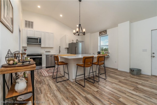 kitchen with pendant lighting, a center island, appliances with stainless steel finishes, a notable chandelier, and white cabinetry