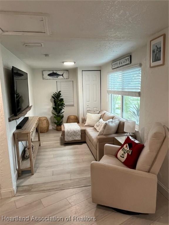 living room with a textured ceiling and light wood-type flooring