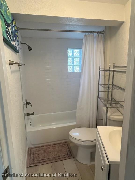 full bathroom featuring tile patterned floors, vanity, shower / bath combination with curtain, and toilet