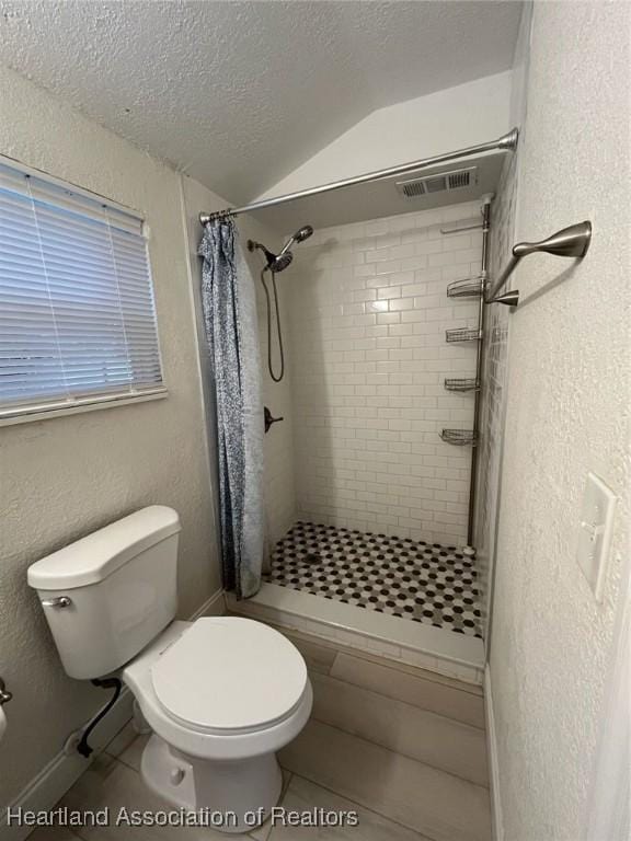 bathroom featuring a shower with curtain, tile patterned flooring, vaulted ceiling, a textured ceiling, and toilet