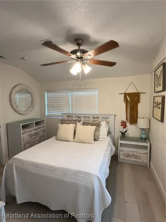 bedroom with ceiling fan, a textured ceiling, and hardwood / wood-style flooring