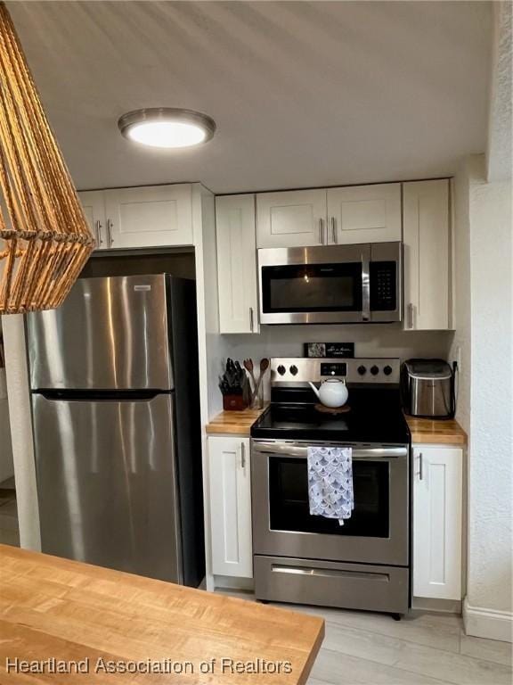 kitchen featuring wood counters, stainless steel appliances, white cabinetry, and light hardwood / wood-style flooring