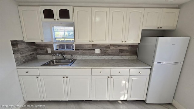 1022 Marble Ave, Avon Park, FL 33825 - kitchen featuring decorative backsplash, freestanding refrigerator, light countertops, white cabinetry, and a sink