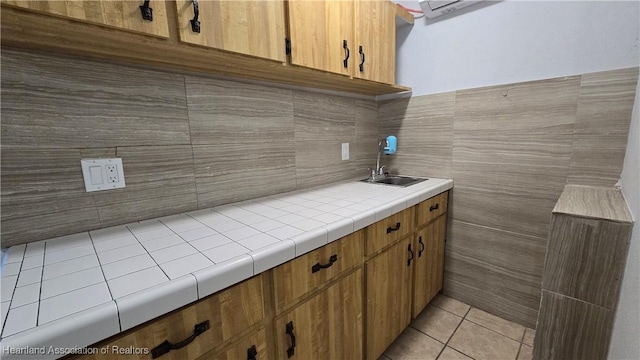 1022 Marble Ave, Avon Park, FL 33825 - kitchen with light tile patterned flooring, a sink, tile walls, tile counters, and brown cabinetry
