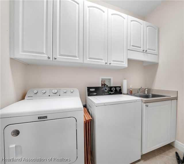 clothes washing area featuring sink, washing machine and dryer, cabinets, and light tile patterned flooring