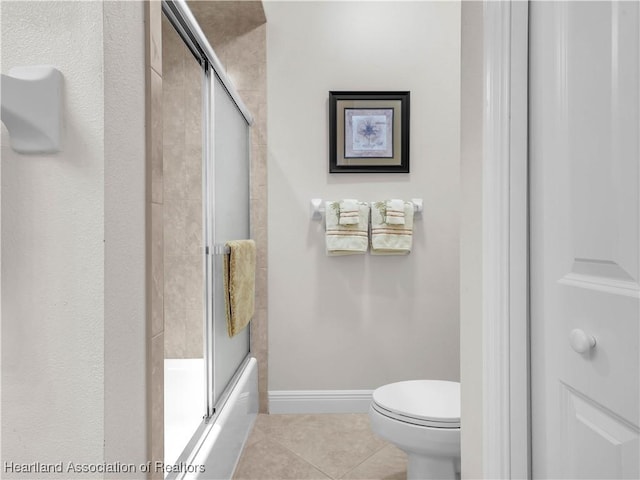 bathroom featuring enclosed tub / shower combo, tile patterned floors, and toilet