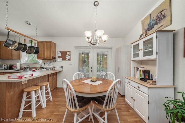 dining room featuring french doors, light hardwood / wood-style flooring, a wealth of natural light, and a chandelier