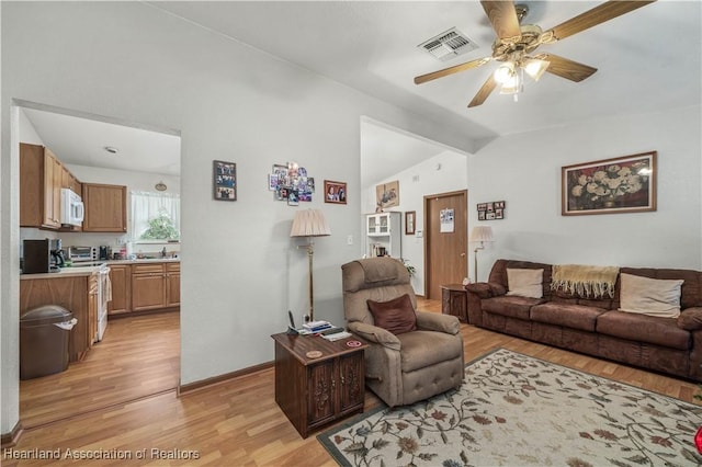 living room featuring light hardwood / wood-style floors, ceiling fan, lofted ceiling, and sink