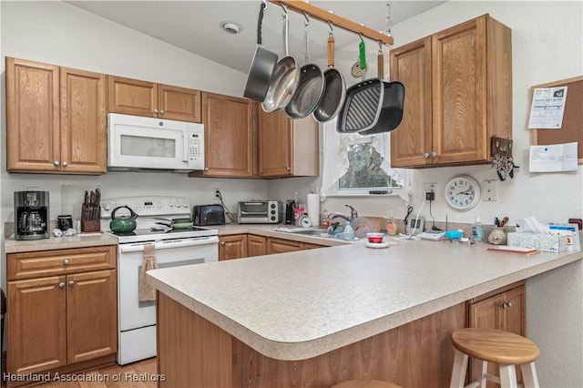 kitchen featuring kitchen peninsula, a breakfast bar, white appliances, vaulted ceiling, and sink