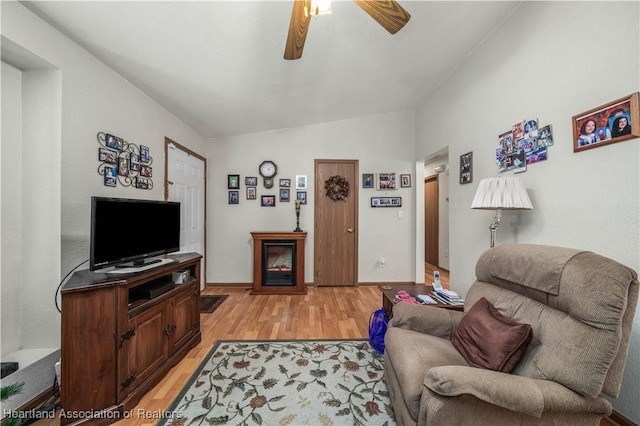 living room with ceiling fan, light hardwood / wood-style flooring, and vaulted ceiling