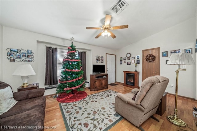 living room with ceiling fan, vaulted ceiling, and hardwood / wood-style flooring