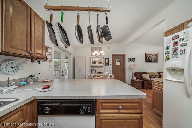 kitchen featuring white fridge with ice dispenser, hanging light fixtures, stainless steel dishwasher, kitchen peninsula, and vaulted ceiling