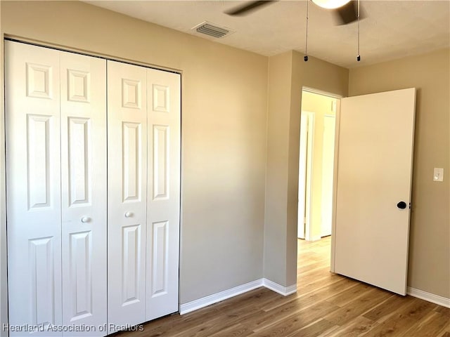 unfurnished bedroom with light wood-type flooring, ceiling fan, and a closet