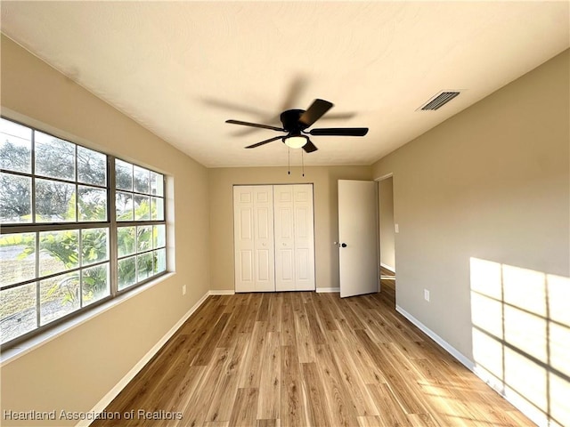 unfurnished bedroom featuring light wood-type flooring, ceiling fan, and a closet