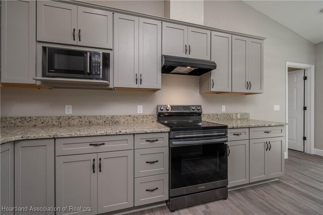 kitchen with electric range, light hardwood / wood-style floors, and light stone counters