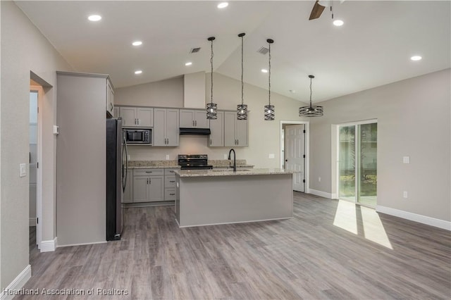 kitchen featuring stainless steel refrigerator, black range with electric stovetop, built in microwave, decorative light fixtures, and a kitchen island with sink