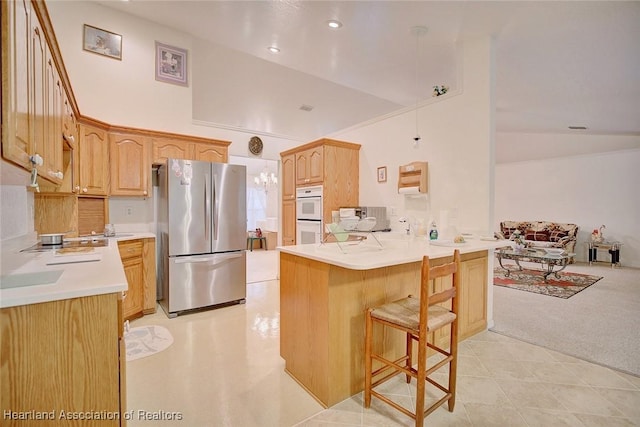 kitchen featuring kitchen peninsula, stainless steel fridge, a kitchen bar, light carpet, and light brown cabinetry