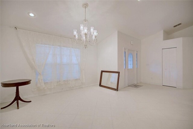 spare room featuring a chandelier, a wealth of natural light, and lofted ceiling