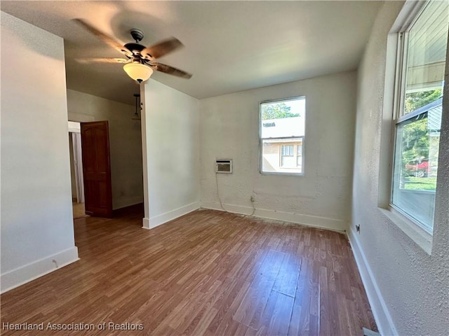 empty room with a wall mounted air conditioner, wood-type flooring, and ceiling fan