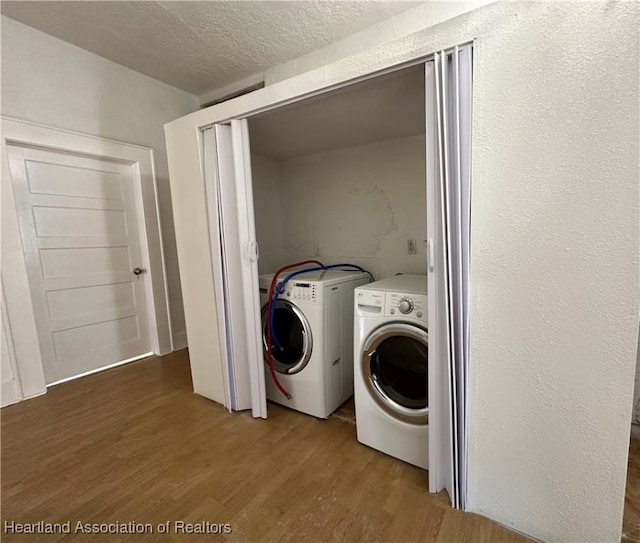 laundry area featuring hardwood / wood-style floors, a textured ceiling, and washing machine and clothes dryer