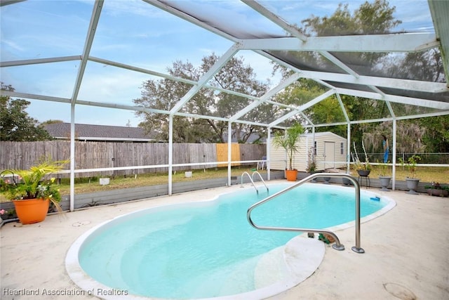 view of swimming pool featuring glass enclosure, a patio area, and a storage shed