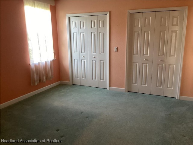 unfurnished bedroom with carpet flooring and two closets