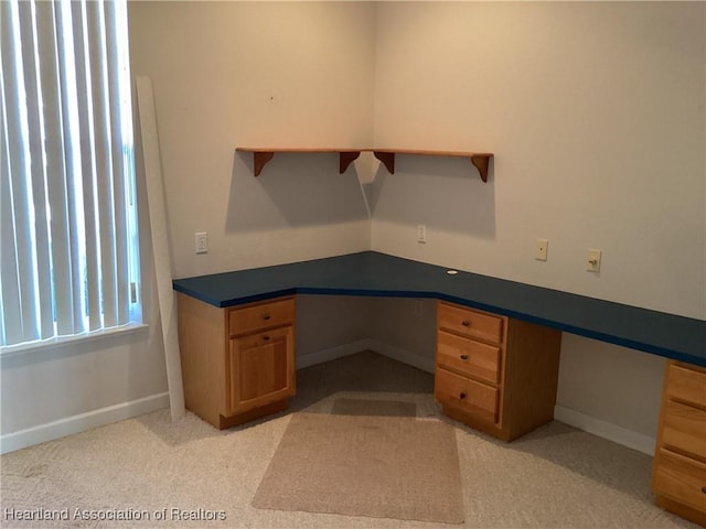 unfurnished office with light colored carpet and built in desk