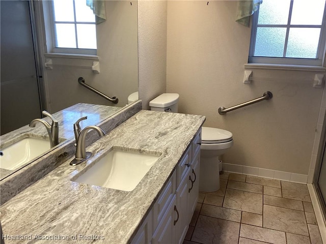 bathroom with tile patterned floors, vanity, toilet, and a wealth of natural light