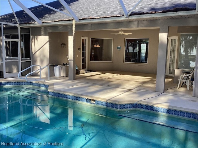 view of swimming pool with ceiling fan, a patio area, and a lanai