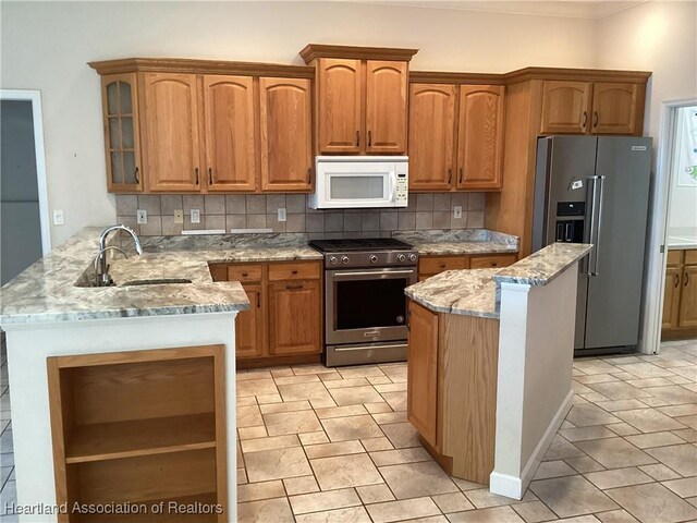 kitchen featuring sink, tasteful backsplash, light stone counters, kitchen peninsula, and appliances with stainless steel finishes