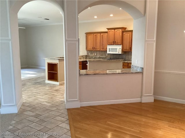 kitchen with light stone counters, ornamental molding, and backsplash