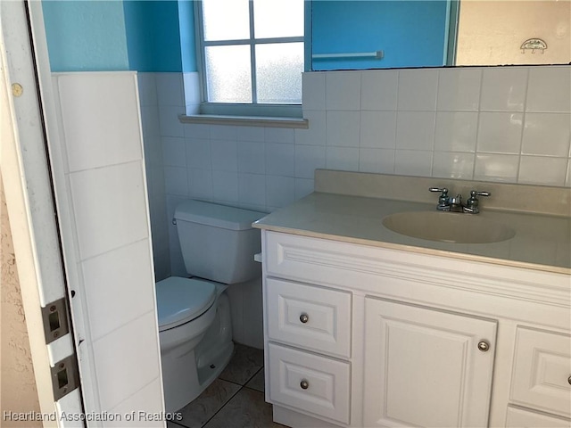 bathroom featuring tile patterned floors, vanity, tile walls, and toilet