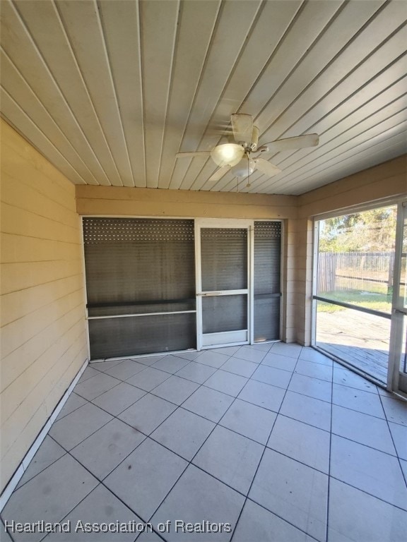 unfurnished sunroom featuring wood ceiling and a ceiling fan