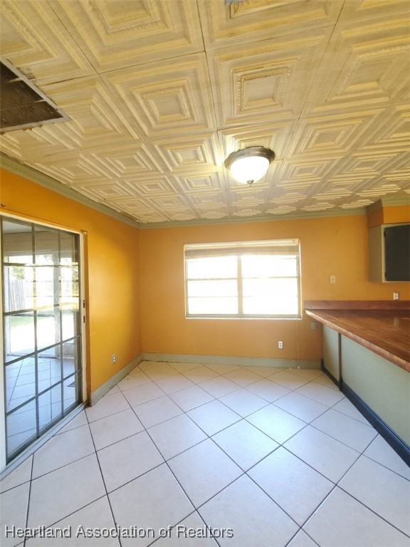 kitchen with light tile patterned floors, an ornate ceiling, and baseboards