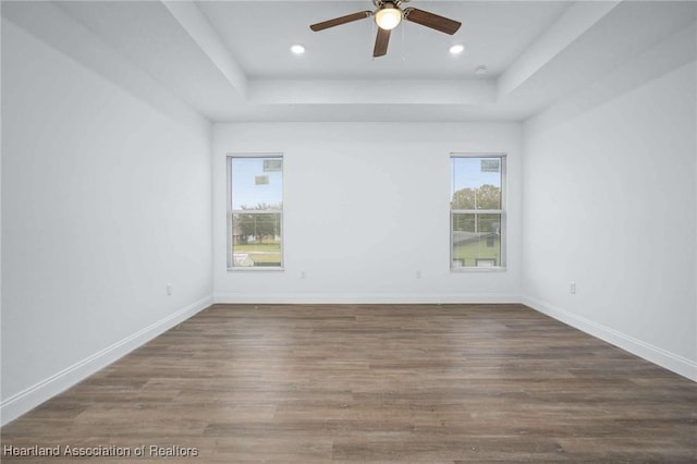 unfurnished room with ceiling fan, dark hardwood / wood-style floors, and a raised ceiling