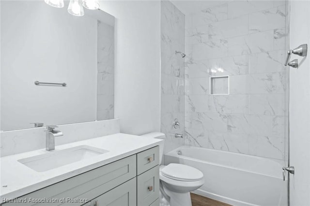 full bathroom featuring tiled shower / bath combo, vanity, and toilet