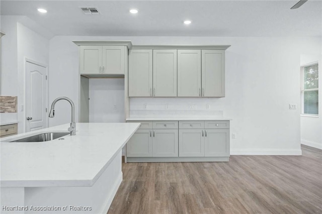 kitchen featuring sink, gray cabinetry, and a kitchen island with sink