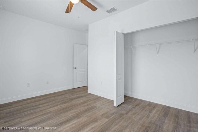 unfurnished bedroom with ceiling fan, a closet, and hardwood / wood-style floors