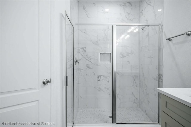 bathroom featuring a shower with shower door and vanity