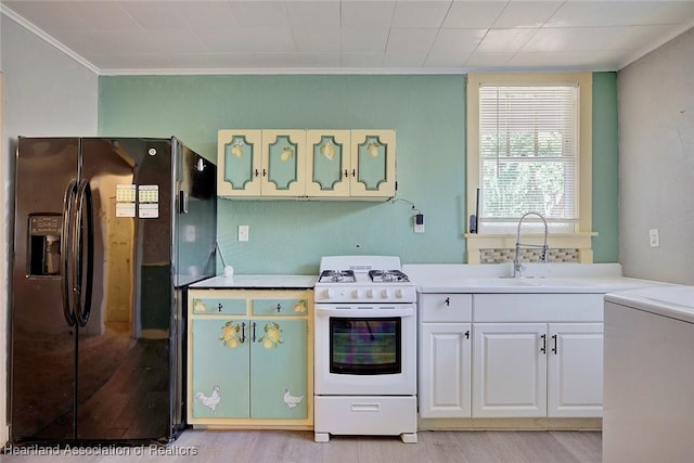 kitchen with white gas range, sink, black fridge, crown molding, and white cabinets