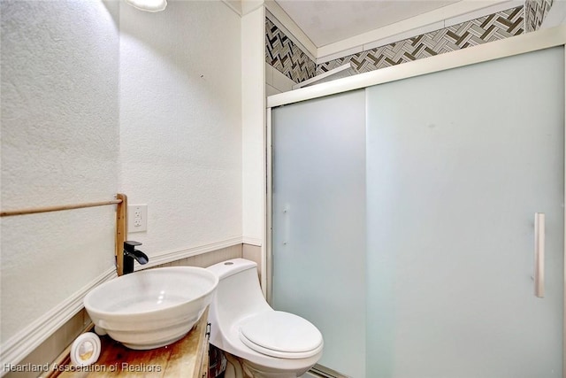 bathroom featuring sink, an enclosed shower, and toilet