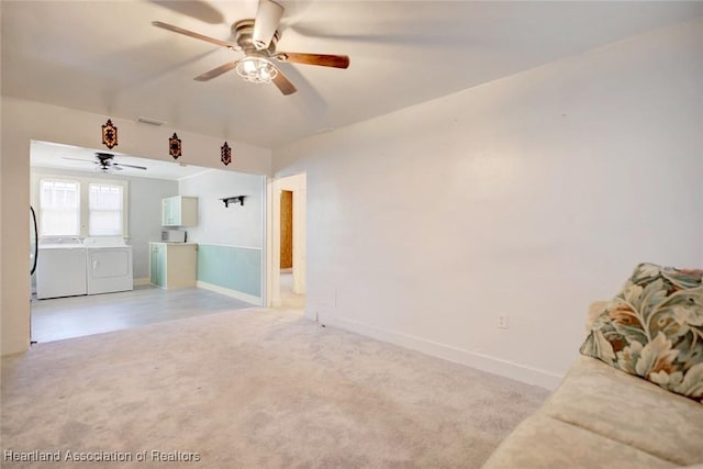 unfurnished living room featuring independent washer and dryer, light colored carpet, and ceiling fan